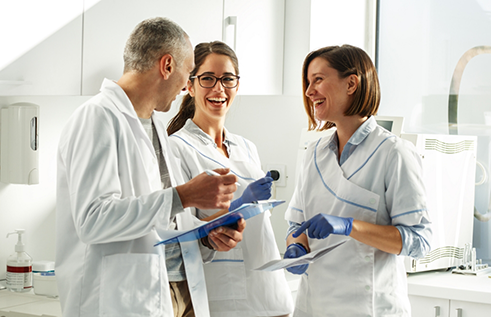 Three dentists holding clipboards and talking