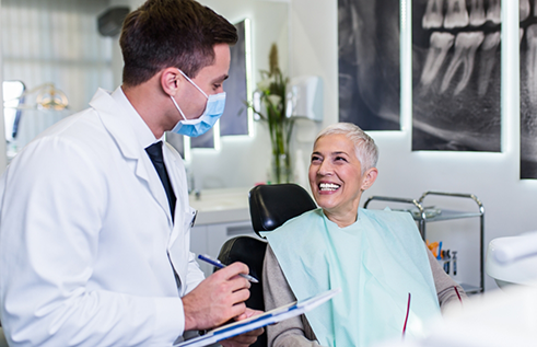 Senior woman in dental chair grinning at her dentist