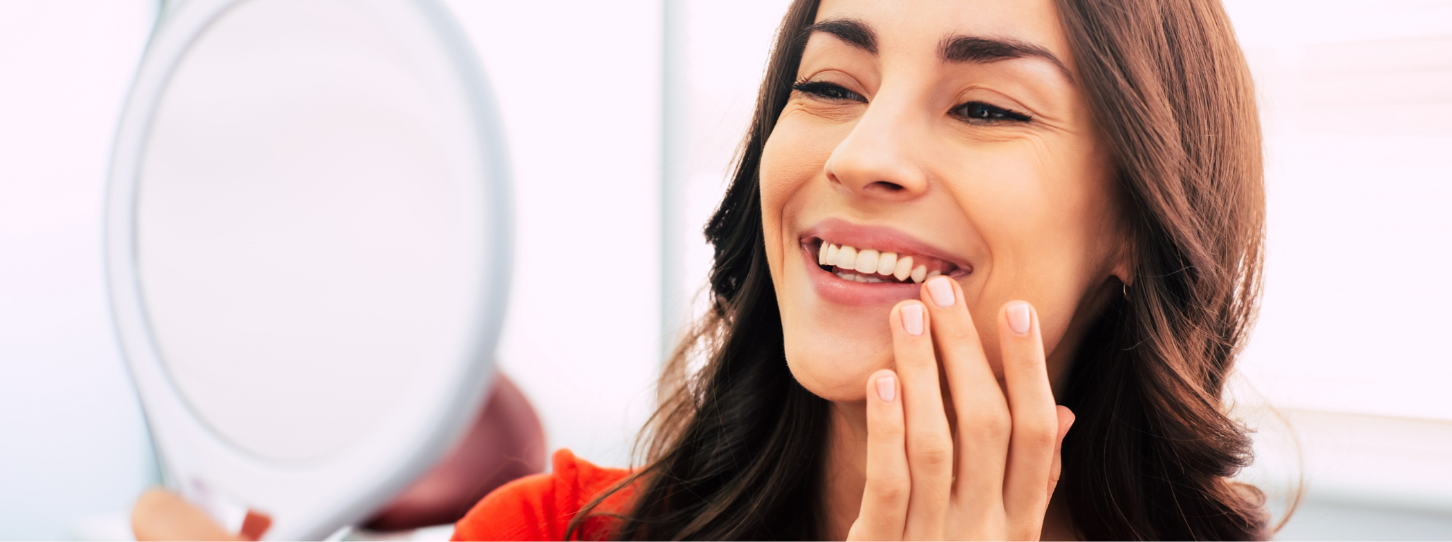 Woman beaming at her reflection after cosmetic dentistry in Lillington