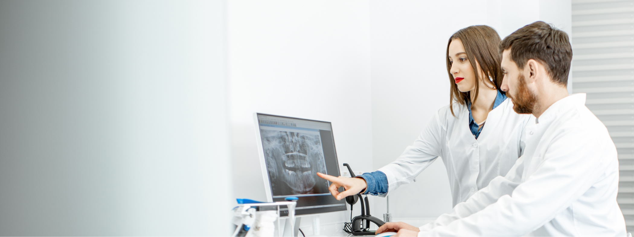 Two dentists looking at x rays of a patients teeth on a computer