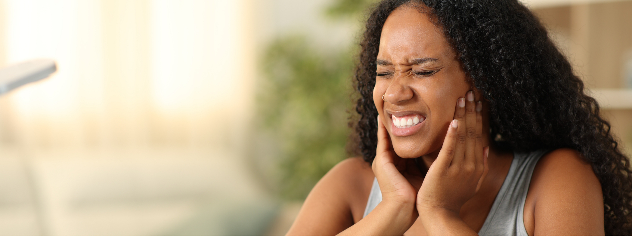 Woman wincing and holding her face in pain before seeing emergency dentist in Lillington