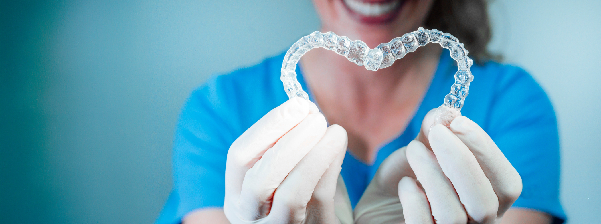 Dentist holding two Invisalign clear aligners in the shape of a heart