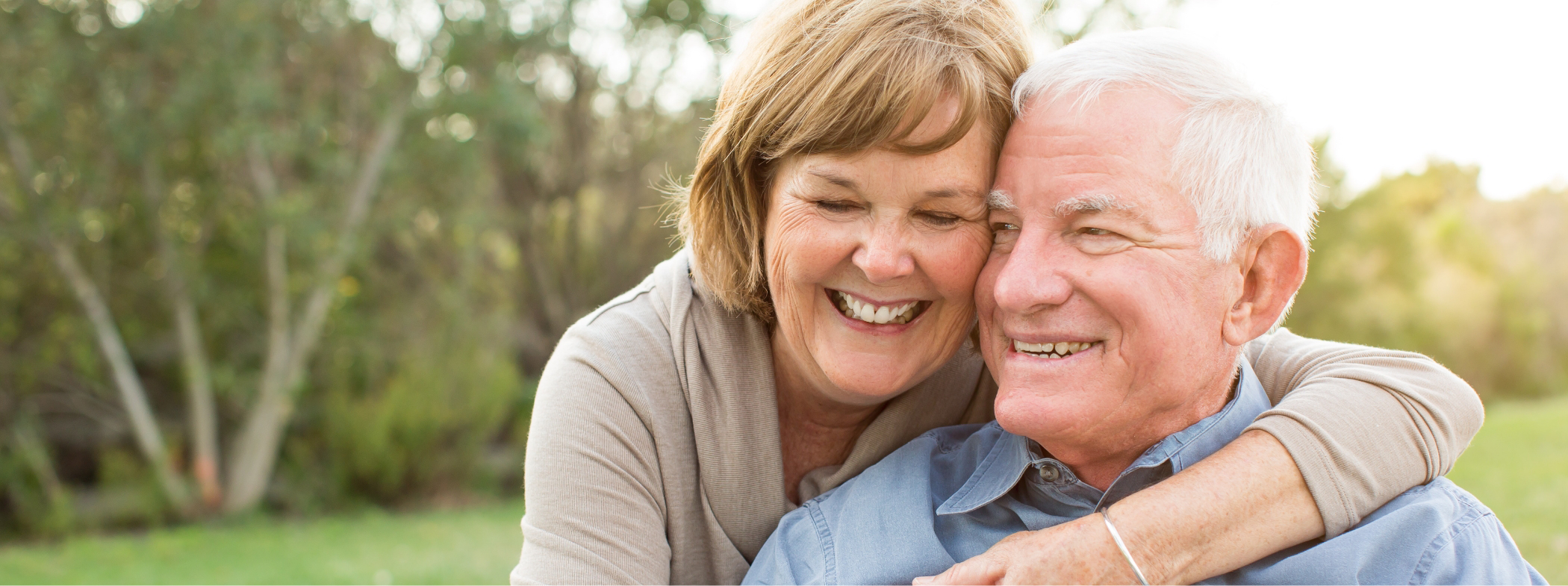 Senior man and woman hugging outdoors after replacing missing teeth in Lillington