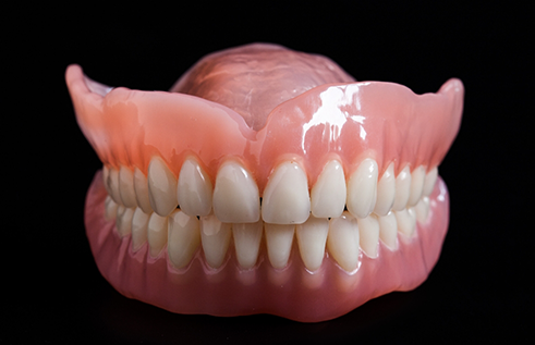 Set of full dentures against black background