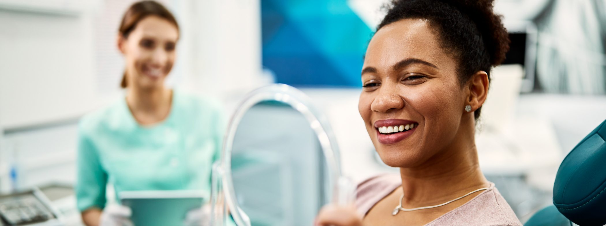 Woman admiring her smile in a mirror after receiving dental services in Lillington