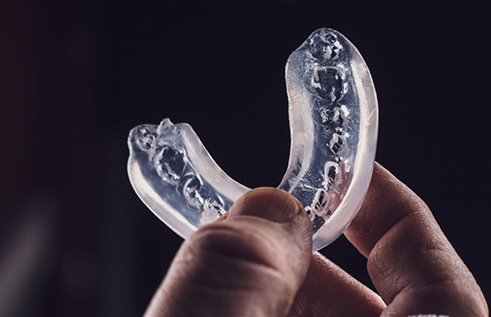 Hand holding a clear athletic mouthguard