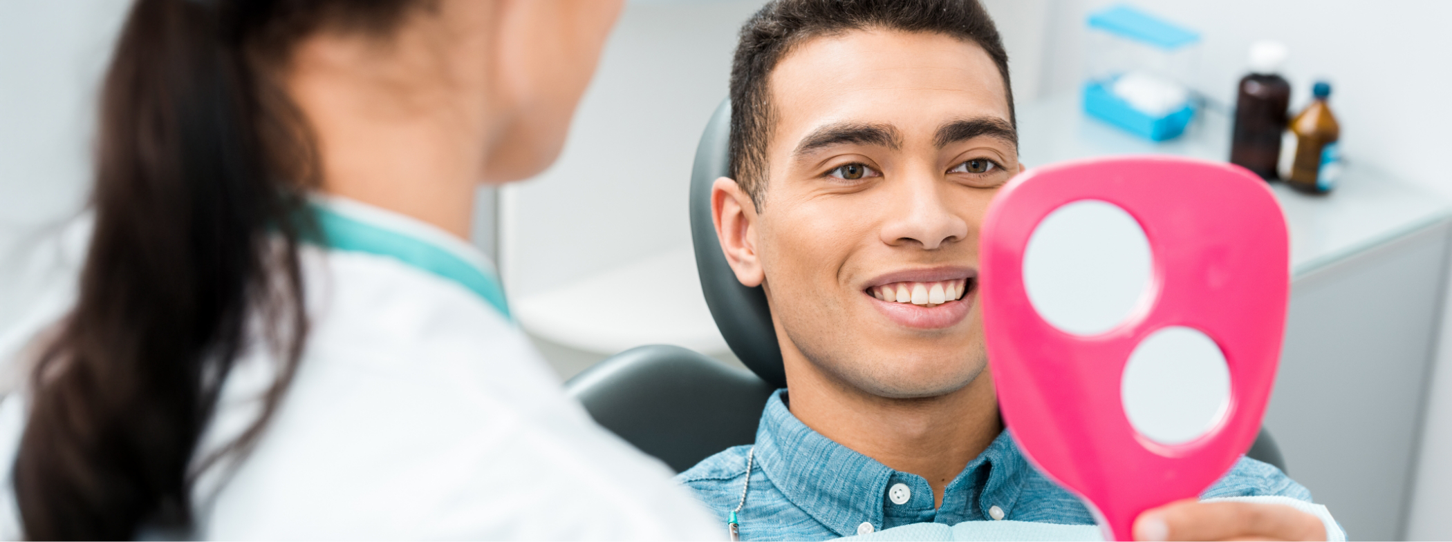 Man in dental chair admiring his smile in a mirror after restorative dentistry in Lillington