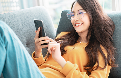 Young woman smiling while scrolling on her phone